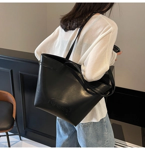 Detailed view of the embossed Nanomara logo on a black high-gloss leather tote bag
