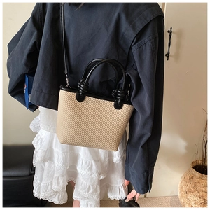 Vue détaillée du sac cabas tressé beige avec poignées en cuir noir et bandoulière