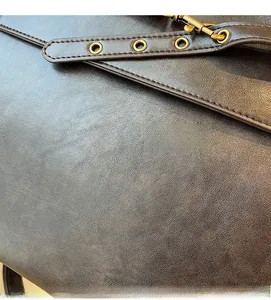 Detailed macro view of dark brown leather texture and golden metal hardware on the bag