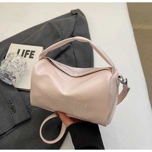 Detail of light pink cylindrical handbag featuring Noronoro embossed text on leather surface