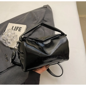 Detail of glossy black oil-wax leather bag with silver metal hardware and logo