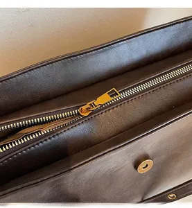 Detailed macro view of the premium golden metal zipper and dark brown leather texture