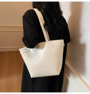 Detail of minimalist white leather tote bag with embossed logo and side buckle detail
