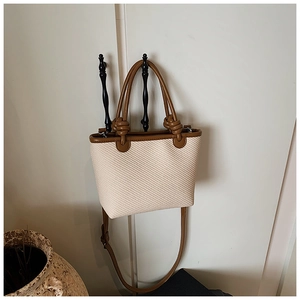 Détail d'un sac cabas tissé avec des poignées en cuir nouées et bordure marron