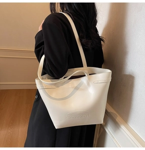 Detail view of the embossed Nomomoro logo on the cream-white leather tote bag
