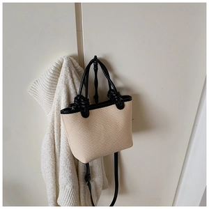 Détail du sac cabas beige tissé avec poignées nouées noires et bandoulière réglable