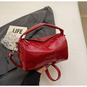 Close-up of red oil wax leather Boston bag featuring Noronoro embossed logo and silver zipper