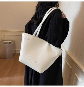 Detail of off-white leather tote bag with Noronoro embossed logo and side strap buckle