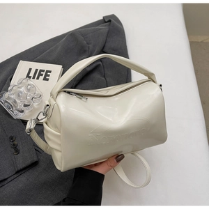 Close-up of cream Boston bag with embossed logo and detachable strap in a lifestyle setting