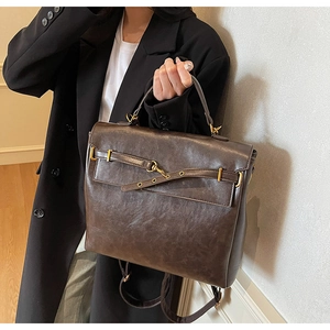 Detail of dark brown vintage faux leather backpack with metallic golden buckle and handle