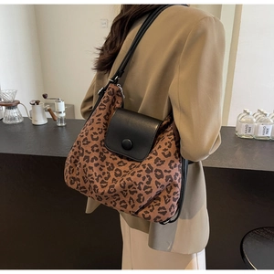 Detailed view of leopard print texture and black leather flap with round decorative buckle