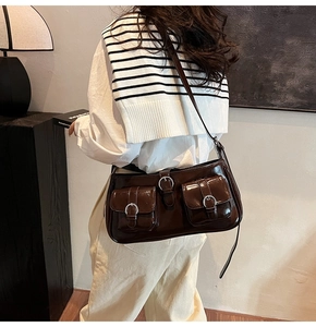 Detail der dunkelbraun glänzenden Ledertasche mit Schnallen und zwei Vordertaschen
