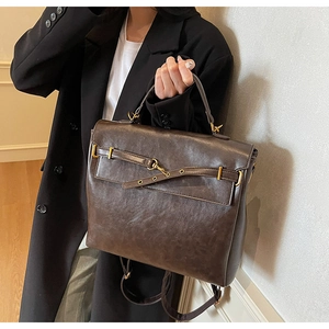 Detail of vintage dark brown faux leather backpack with metallic gold buckles and straps