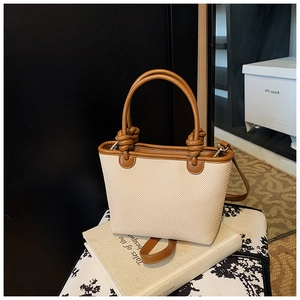 Détails du sac seau en tissu tressé avec poignées en cuir marron et design à nœuds