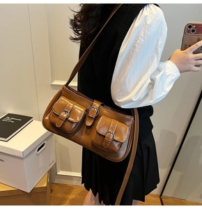 Detail der braunen Kunstleder-Schultertasche mit vorderen Doppeltaschen und Metallschnallen