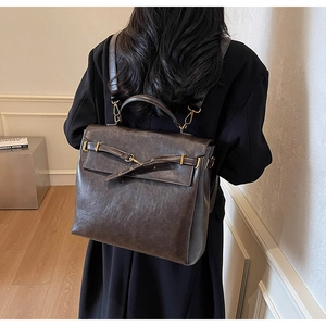 Detail of vintage brown leather backpack with golden buckle and slim straps on model