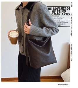 Détail du sac seau en cuir marron foncé avec texture plissée porté à l'épaule
