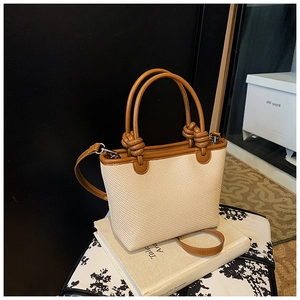 Détail d'un sac cabas tissé avec poignées en cuir marron et bandoulière réglable