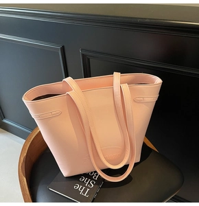 Detail of light pink leather tote bag with embossed oval logo on a black textured chair