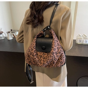 Close-up of leopard print convertible backpack worn by a model in a cozy cafe setting