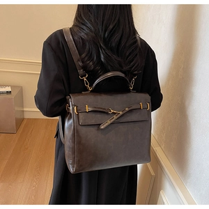 Detail view of a vintage dark brown leather backpack with gold buckles in a lifestyle setting
