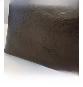 Gros plan du sac seau en cuir marron foncé avec logo embossé et texture plissée