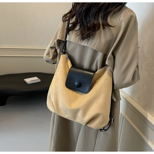 Detail of ginger suede tote bag with black leather flap and button accent on model