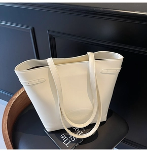 Detail shot of cream white leather tote bag with embossed logo on premium textured finish