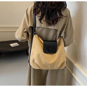Detail of a large suede tote bag in mustard yellow worn with a classic trench coat