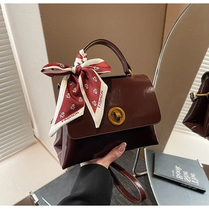 Detail of dark brown retro shoulder bag with glossy leather texture and panda silk scarf