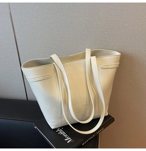 Close-up of cream leather tote bag with embossed logo on black magazine background