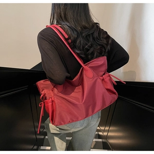 Détail du grand sac cabas rouge en nylon avec nœuds à cordon porté par un mannequin