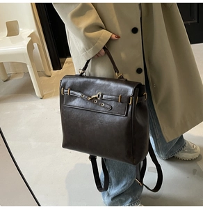 Detail of vintage dark brown faux leather backpack with metallic buckle and carry handle