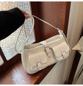 Detailansicht der cremefarbenen PU-Schultertasche mit silbernen Metallschnallen am Fenster
