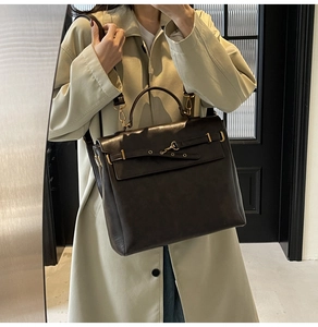 Detail of dark brown matte leather satchel featuring a belt-style metal buckle and strap