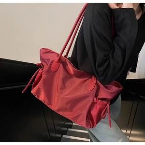 Vue latérale du grand sac de voyage rouge avec cordon de serrage et anses en cuir