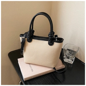Détail d'un sac seau bicolore en paille tressée avec des finitions en cuir noir