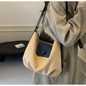 Detail of khaki suede tote bag with black leather flap and shoulder strap on model