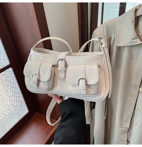 Detailansicht einer cremefarbenen Ledertasche mit Taschen und Schnallenverzierung