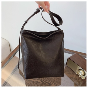 Détail du sac seau marron foncé avec texture froissée vintage et logo discret