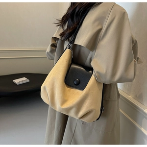 Detail of beige suede tote bag with black leather flap and button closure worn by model