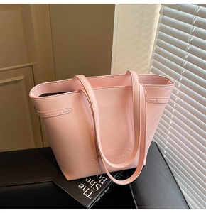 Detail of embossed Niamoro logo and decorative side strap on pink leather tote bag