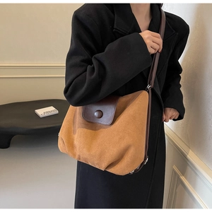 Brown suede tote bag with round buckle detail shown on a model in a black coat