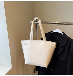 Detail of cream tote bag with Noronoro logo hanging on a sleek metal hanger