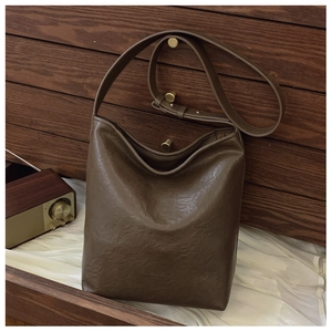 Détail de la texture cuir marron foncé plissé et logo embossé sur le sac à bandoulière