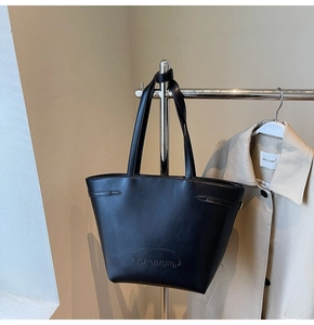 Detail shot of the embossed Nonopolo logo on a black large matte leather tote bag