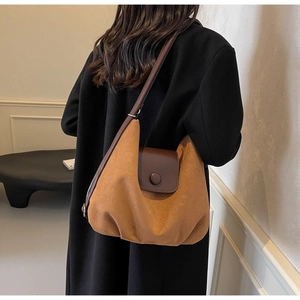 Detail view of the brown suede tote bag texture and leather flap on a shoulder bag