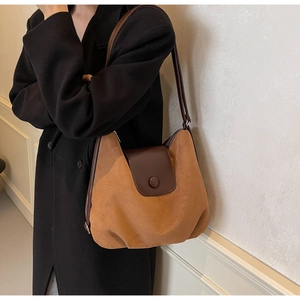 Detail of suede and leather caramel shoulder bag with a round button closure