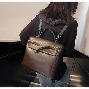 Detail of vintage dark brown leather backpack with gold hardware and flap closure design