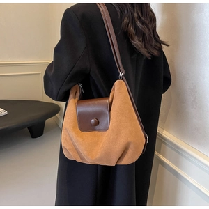 Close-up of caramel brown suede tote bag with adjustable strap on black coat